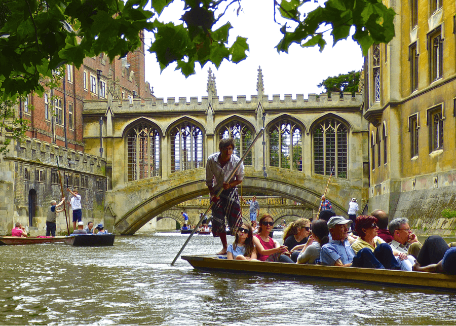 Guided punt with tour guide on the end skillfully poling the punt along the river cam.