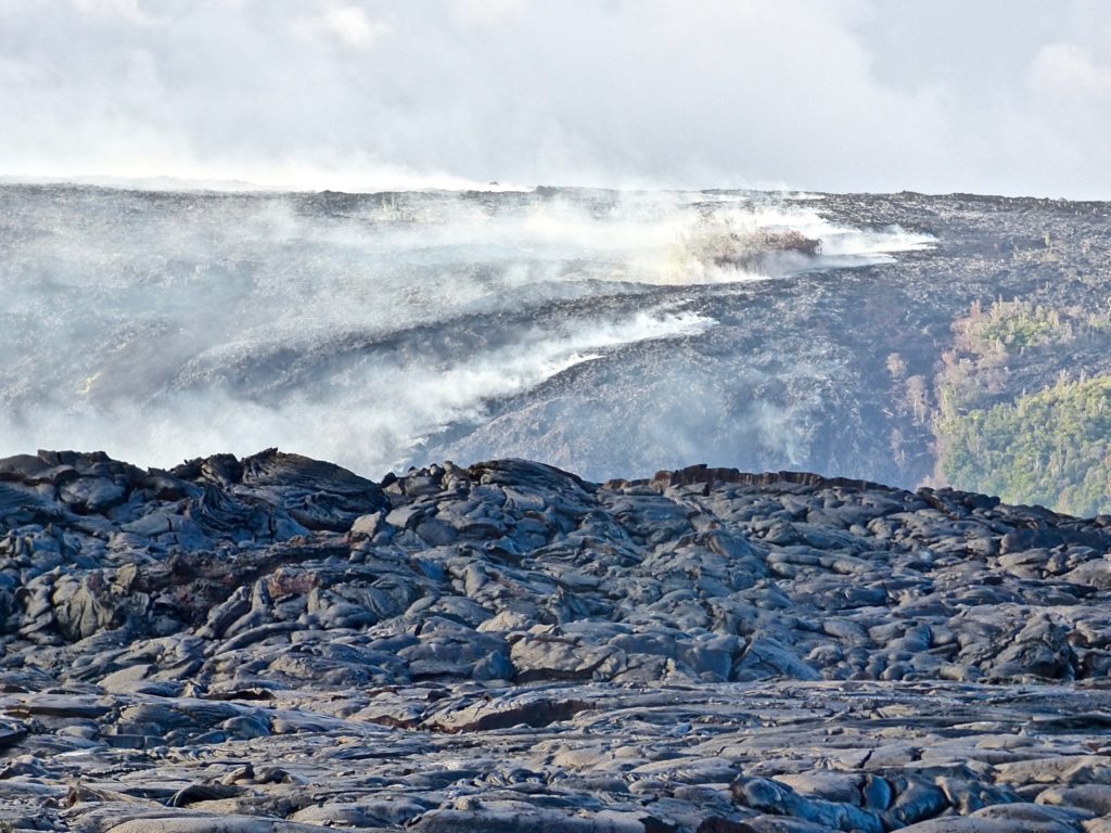 Molten lava from Volcano National Park steams down the hillside.