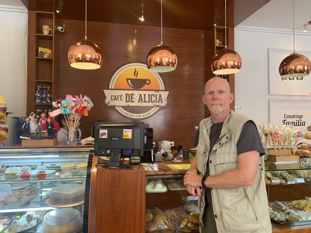 Jack at the counter of Cafe de Alicia ordering cappuccino with his limited essential spanish.