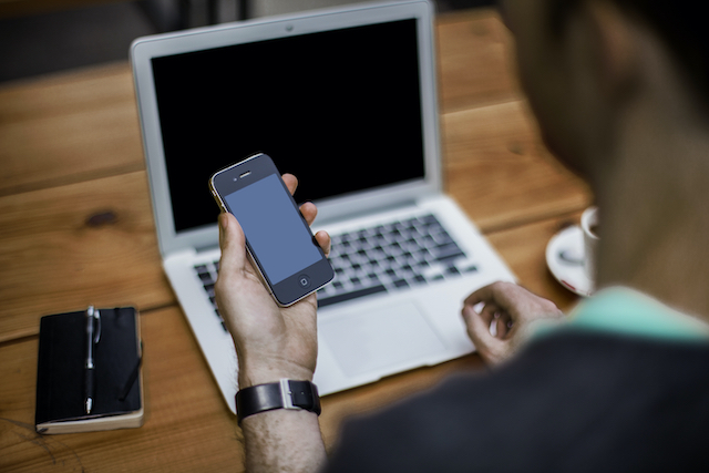 Man at a desk with computer and cell phone