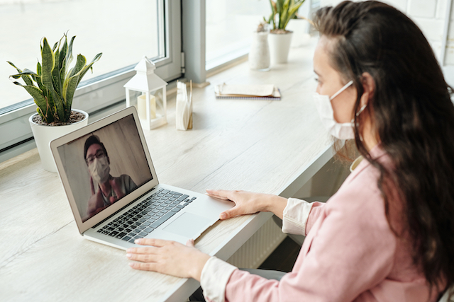 Woman sitting at desk video calling another person.