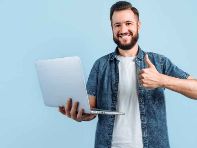 Man holding laptop giving a thumbs up because he successfully used his companion pass.
