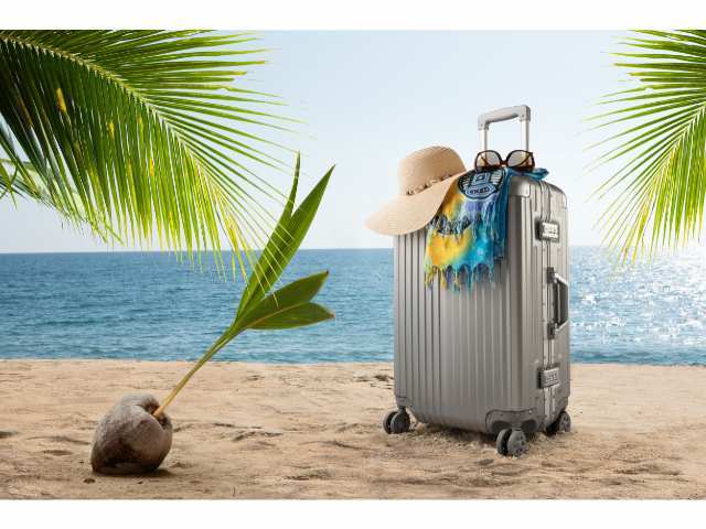 Suitcase on a beach like packing for your Kauai vacation