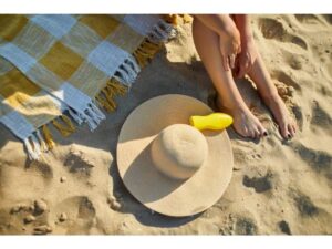 Picture of woman putting on sunscreen on the beach. It must be reef safe.