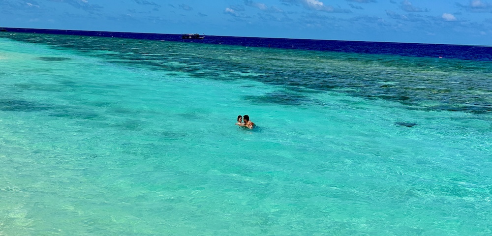 Two people playing in the turquoise colored water of the Maldives