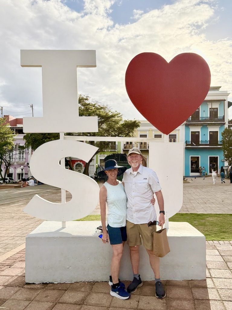 Two people standing in front of a big 3-d sign that says I "heart" SJ. in San Juan Puerto Rico