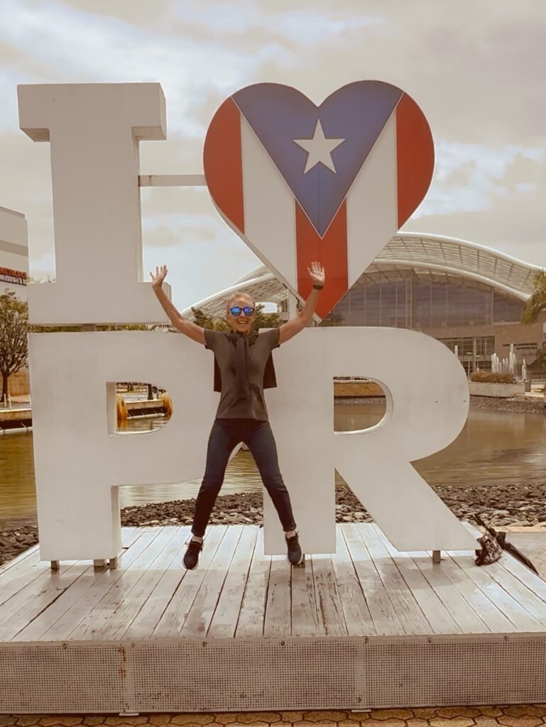 Lady jumping in front of I "heart' PR sign.