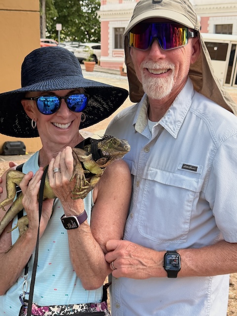 man and a woman standing with the woman holding a green iguana in San Juan Old Town Puerto Rico