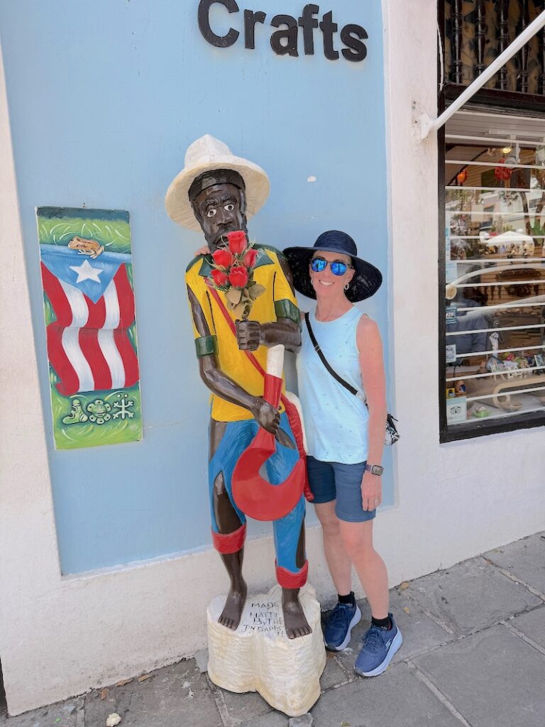 Lady in hat standing by a statue outside of a craft store in Old San Juan Puerto Rico